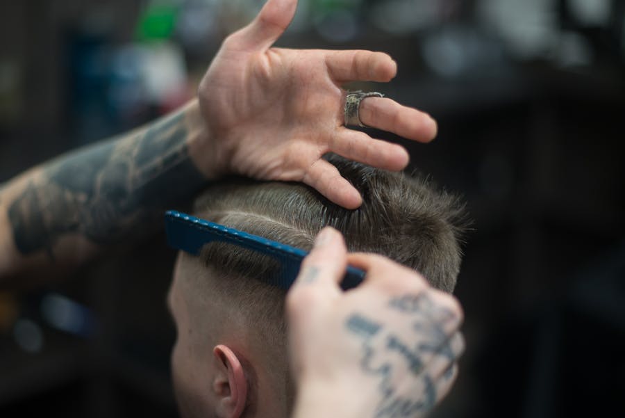 Barber combing a fresh fade from behind
