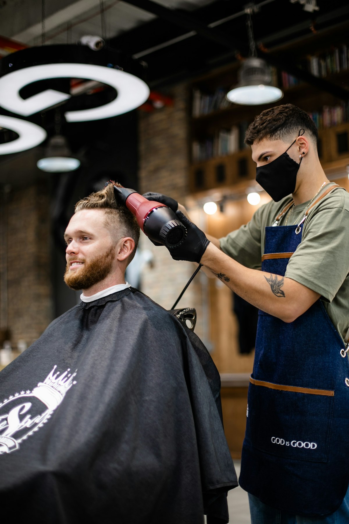 Barber styling a fresh men's fade with a blow dryer